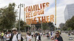 FILE - Demonstrators hold signs as they participate in the "Families Belong Together: Freedom for Immigrants" march, June 30, 2018, in Los Angeles. 