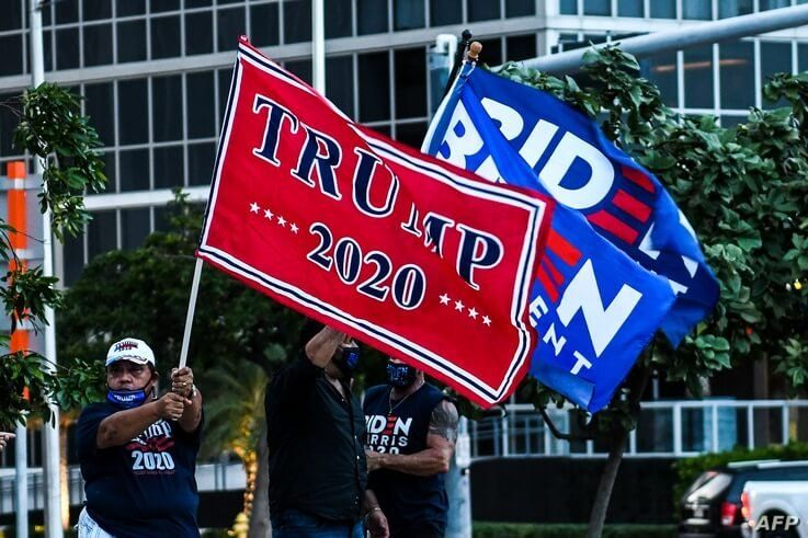 Supporters of US President Donald Trump and Democratic presidential nominee and former Vice President Joe Biden wave flags…