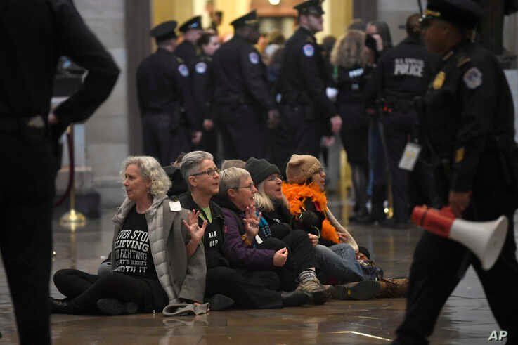 Protesters demonstrate against President Donald Trump by sitting on the floor of the Rotunda on Capitol Hill in Washington,…