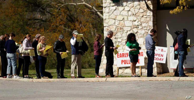 In this Friday, Feb. 28, 2020 photo, voters wait in line at an early polling site in San Antonio.  California and Texas are the…