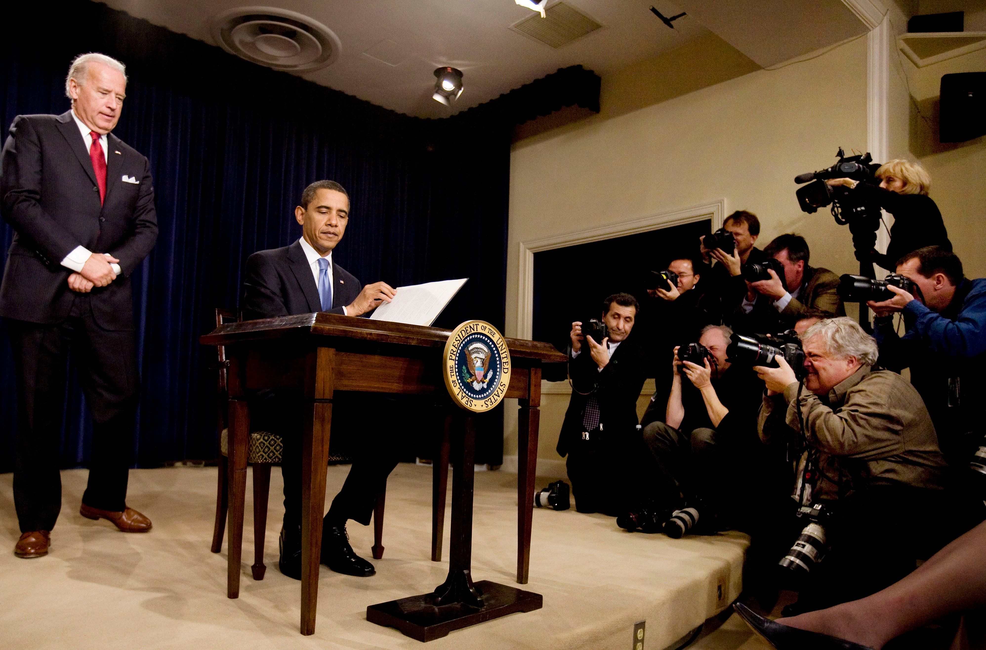 FILE - US Vice President Joseph Biden (L) watches as President Barack Obama signs an executive order on Executive Branch ethics as news photographers document at the Eisenhower Executive Office Building in the White House, Washington, Jan. 21, 2009. 