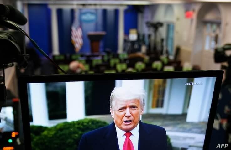 US President Donald Trump is seen on TV from a video message released on Twitter addressing rioter at the US Capitol, in the…