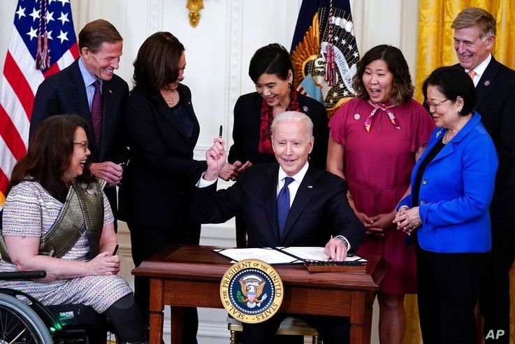 President Joe Biden hands out a pen after signing the COVID-19 Hate Crimes Act, in the East Room of the White House, Thursday,…