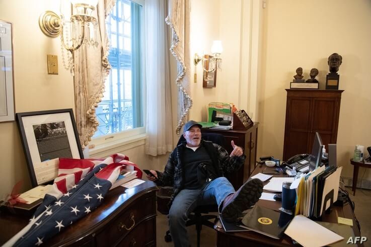 A supporter of US PreA supporter of President Donald Trump sits inside the office of Speaker of the House Nancy Pelosi inside the Capitol in Washington, Jan. 6, 2021. sident Donald Trump sits inside the office of US Speaker of the House Nancy Pelosi as he protest inside…