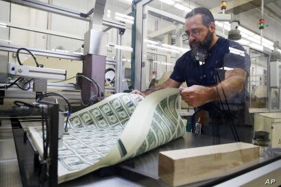 FILE - A worker aerates printed sheets of dollar bills at the Bureau of Engraving and Printing in Washington, Nov. 15, 2017.