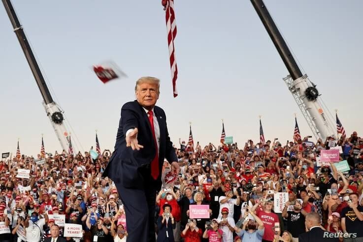 U.S. President Donald Trump throws a face mask from the stage during a campaign rally in Sandford, Fla.