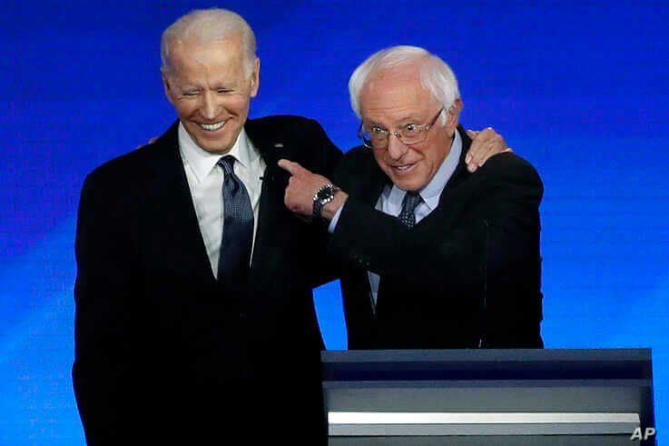 Former Vice President Joe Biden, left, embraces Sen. Bernie Sanders, I-Vt., during a Democratic presidential primary debate,…