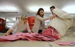 Election workers Heidi McGettigan, left, Margaret Wohlford, center, and David Jensen, unload a bag of ballots brought in a from a polling precinct to the Sacramento County Registrar of Voters office in Sacramento, Calif., June 5, 2018.