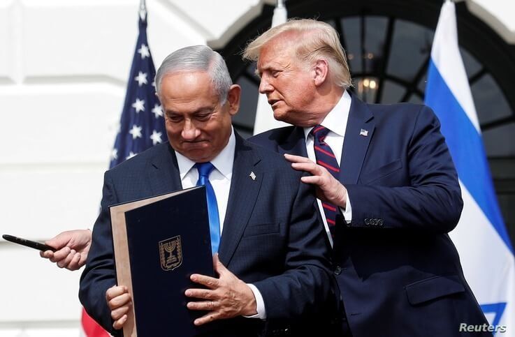 Israel's Prime Minister Benjamin Netanyahu stands with U.S. President Donald Trump after signing the Abraham Accords,…