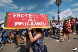 FILE - Supporters of the Deferred Action for Childhood Arrivals, or DACA chant slogans and carry signs while joining a Labor Day rally in downtown Los Angeles.