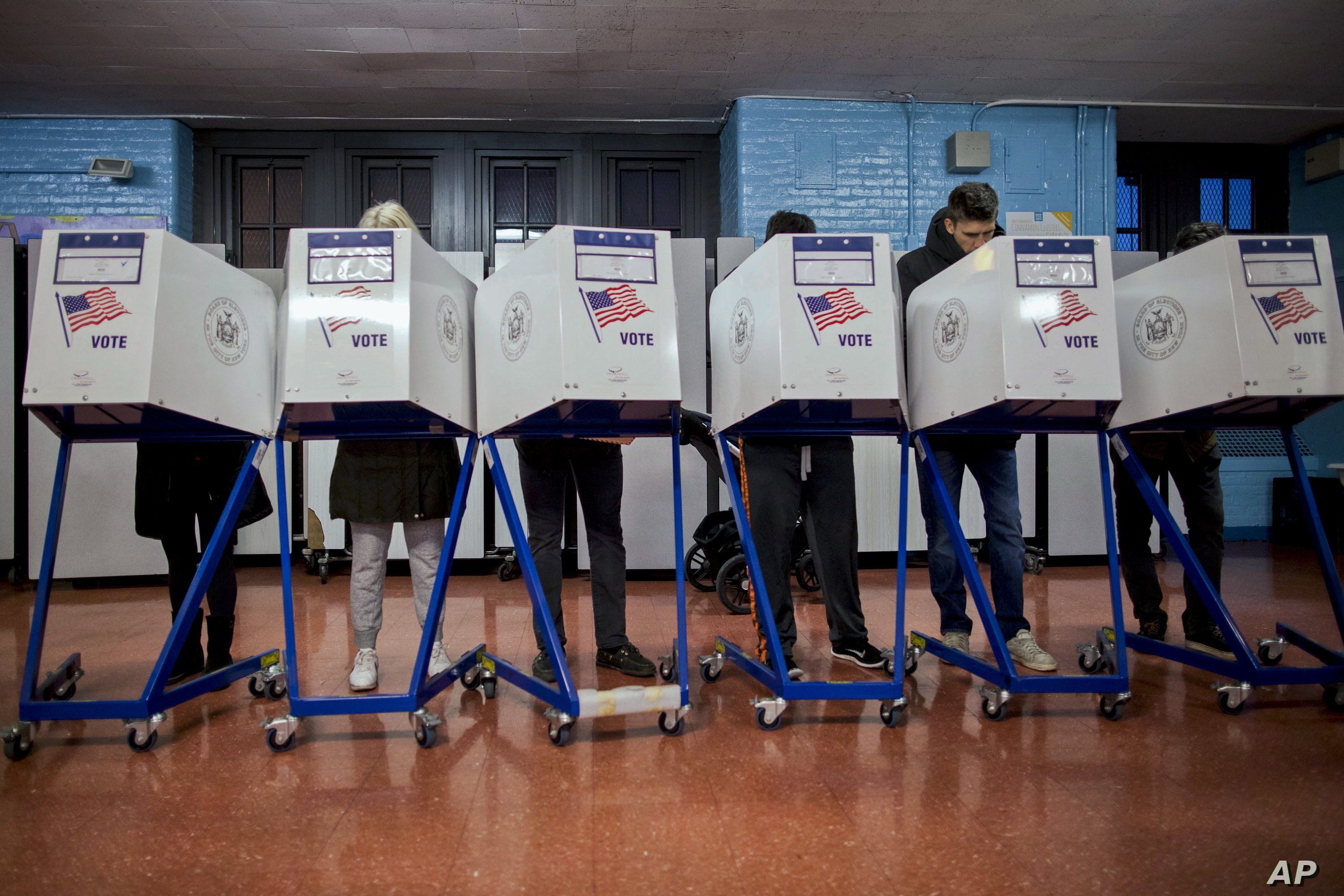 FILE - Voters fill out their forms as they prepare to vote at a polling station in the Brooklyn borough of New York, Nov. 8, 2016.