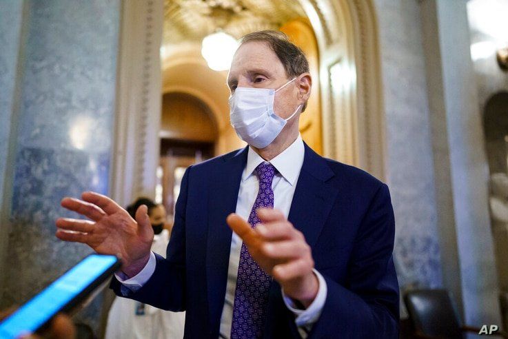 Sen. Ron Wyden, D-Ore., chair of the Senate Finance Committee, stops for a reporter as the Senate votes to advance the $1…