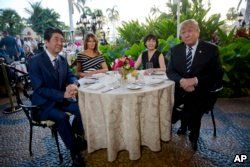 FILE - President Donald Trump and first lady Melania Trump sit with Japanese Prime Minister Shinzo Abe and his wife, Akie Abe, for dinner at Trump's private Mar-a-Lago club, April 17, 2018, in Palm Beach, Fla.