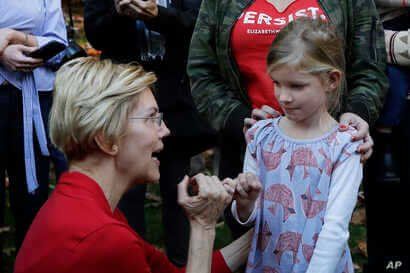 Democratic presidential candidate Sen. Elizabeth Warren, D-Mass., makes her signature pinky promise with Nora Showalter, 6, at…