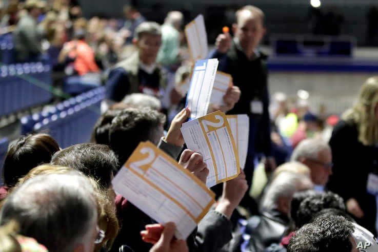 Caucus goers seated in the section for Democratic presidential candidate former Vice President Joe Biden hold up their first…