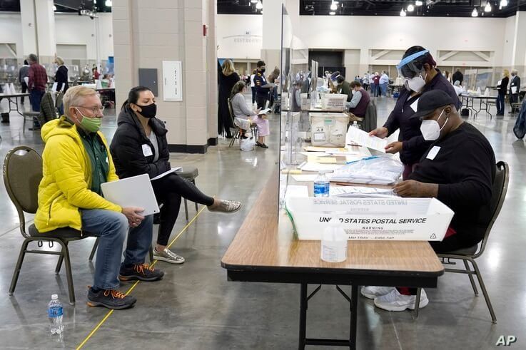 Election workers, right, verify ballots as recount observers, left, watch during a Milwaukee hand recount of presidential votes at the Wisconsin Center, in Milwaukee, Wisconsin, Nov. 20, 2020.