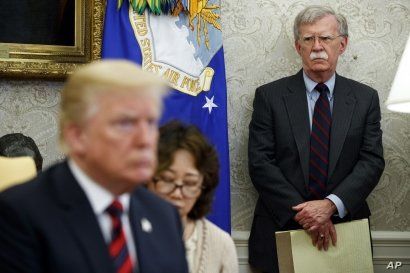 U.S. President Donald Trump, left, conducts a meeting in the Oval Office of the White House in Washington, May 22, 2018, as then-National Security Adviser John Bolton, right, looks on. 
