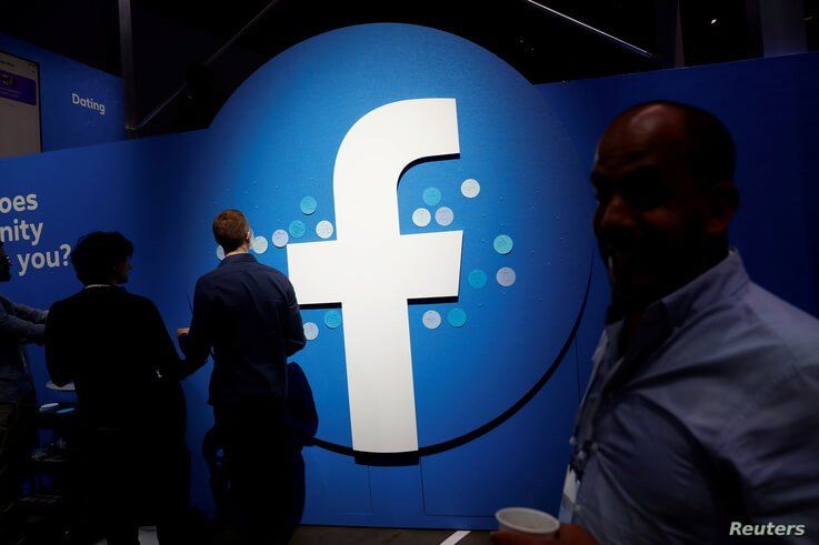FILE - Attendees walk past a Facebook logo during Facebook Inc's F8 developers conference in San Jose, California, United States.