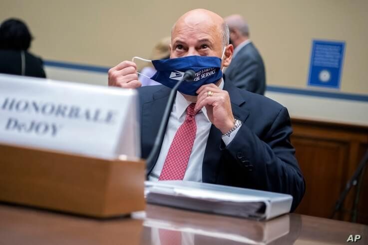 Postmaster General Louis DeJoy removes his face mask as he arrives to testify before a House Oversight and Reform Committee.