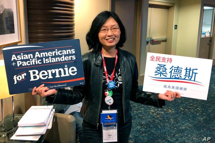 Una Lee Jost, a lawyer from Pasadena, Calif., holds signs supporting Bernie Sanders at the California Democratic Convention in…