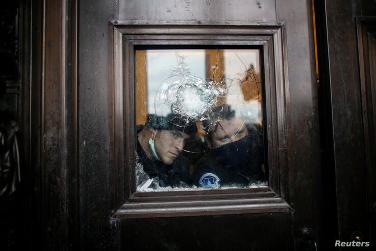Members of the Capitol police look through a smashed window as pro-Trump protesters rally to contest the certification of the…