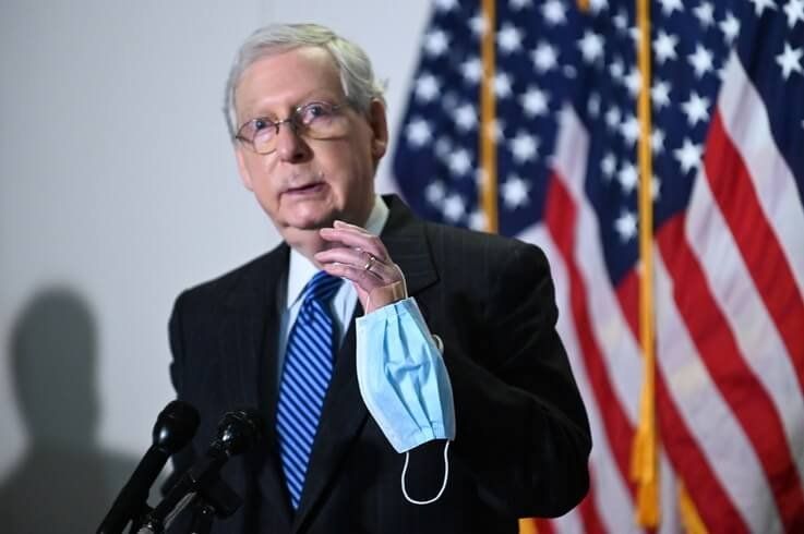 Senate Majority Leader McConnell holds a face mask while participating in a news conference at the U.S. Capitol in Washington
