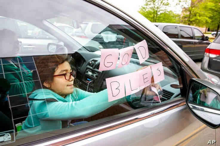 FILE - In this May 5, 2020, file photo, Elizabeth Ruiz, 7, puts up post-it notes on her mother's car window that spell out 