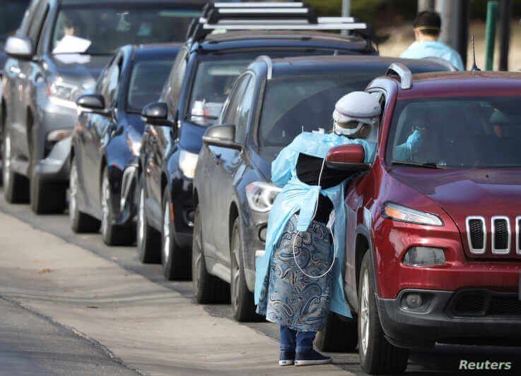 Health care workers test people at a drive-thru testing station run by the state health department, for people who suspect they…