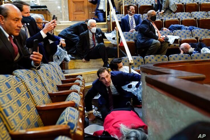 People shelter in the House gallery as protesters try to break into the House Chamber at the U.S. Capitol on Wednesday, Jan. 6,…