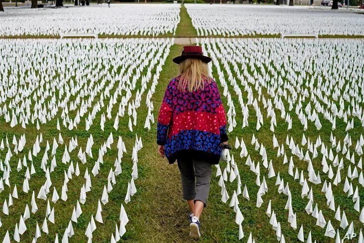 FILE - Artist Suzanne Brennan Firstenberg walks among thousands of white flags planted in remembrance of COVID deaths.