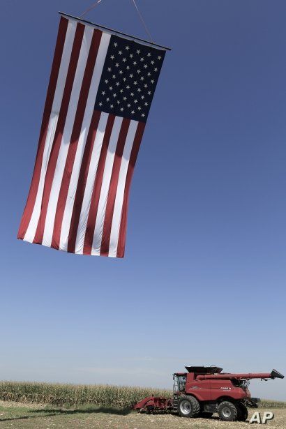 A Case combine gets ready for a corn harvesting demonstration under a giant flag, at the Husker Harvest Days farm show in Grand Island, Neb., Tuesday, Sept. 10, 2019. (AP Photo/Nati Harnik)