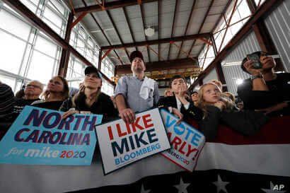 People listen as Democratic presidential candidate and former New York City Mayor Mike Bloomberg speaks at a campaign event in…