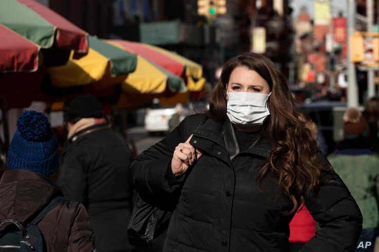 A woman, who declined to give her name, wears a mask in New York, Jan. 30, 2020. She works for a pharmaceutical company and said she wears the mask out of concern for the coronavirus. 