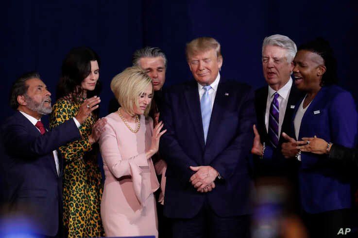 Faith leaders pray with President Donald Trump during a rally for evangelical supporters at the King Jesus International…