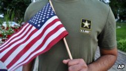 A Pakistani recruit, 22, who was recently discharged from the U.S. Army, holds an American flag as he poses for a picture, July 3, 2018. The man asked his name and location to be undisclosed for safety reasons. The AP interviewed three recruits from Brazil, Pakistan and Iran, all of whom said they were devastated by their unexpected discharges.