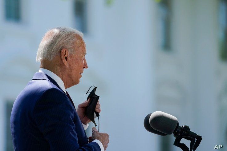 President Joe Biden removes his face mask to speak about COVID-19, on the North Lawn of the White House, Tuesday, April 27,…