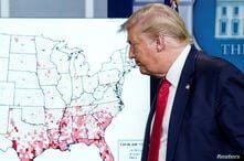 President Donald Trump walks past a U.S. map of reported coronavirus cases as he departs following a coronavirus briefing.