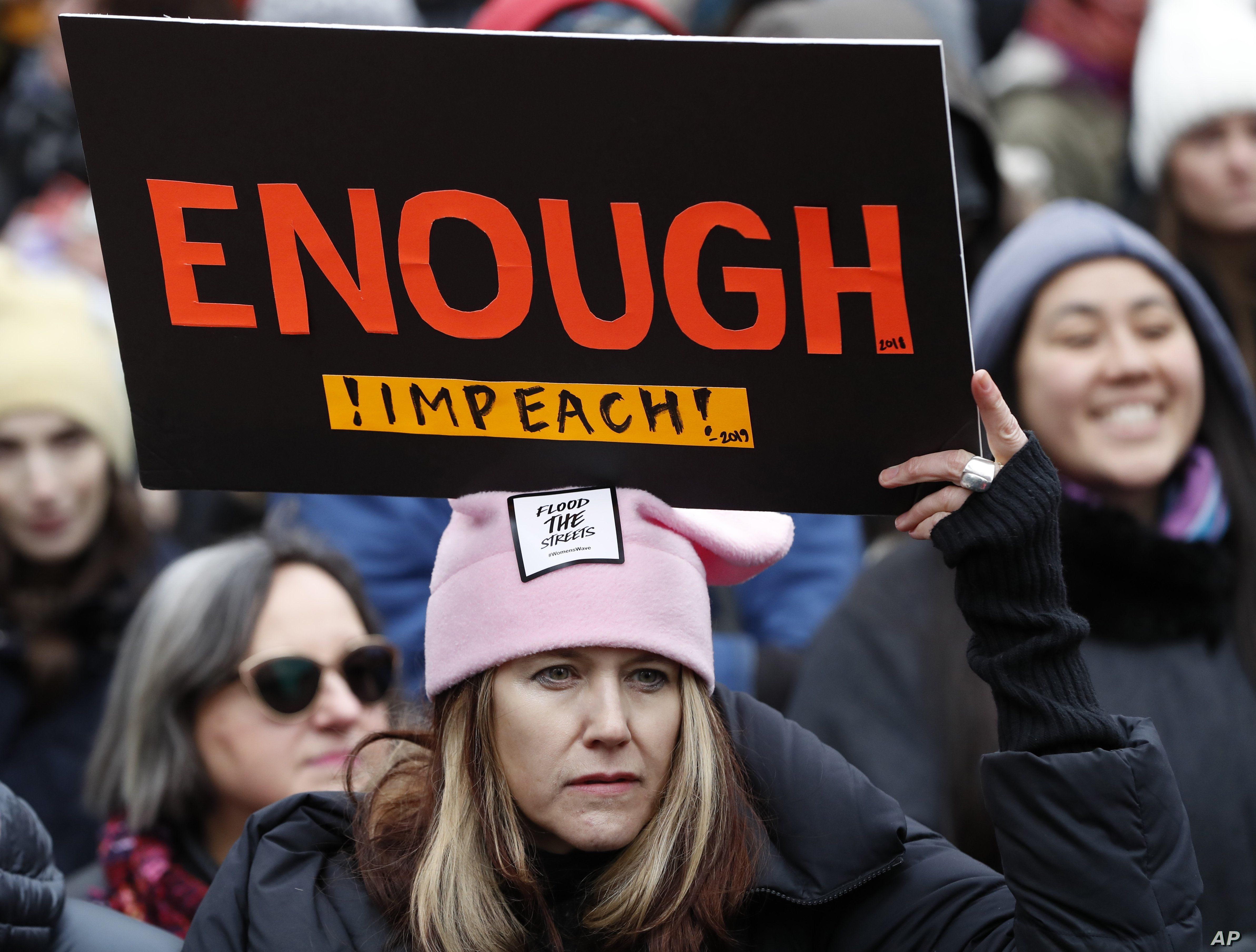 FILE - A woman holds a sign expressing her opinion about impeaching President Donald Trump at a rally organized by Women's March NYC at Foley Square in Lower Manhattan, Jan. 19, 2019, in New York. 