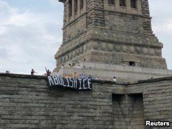 The group Rise and Resist stages a protest at the Statue of Liberty in New York, July 4, 2018, in this picture obtained from social media. (Rise and Resist/via Reuters)