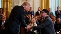 President Donald Trump shakes hands with acting Department of Veterans Affairs Secretary Robert Wilkie after announcing he will nominate him to lead the department during an event on prison reform at the White House, May 18, 2018, Washington. 
