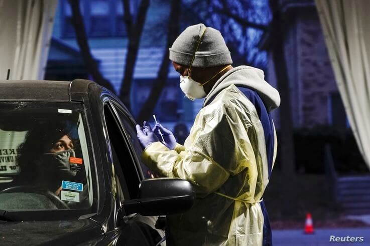 Certified nursing assistant (CNA) Jermaine LeFlore prepares to take a patient's nasal swab at a drive-thru testing site outside the Southside Health Center in Milwaukee, Wisconsin, Oct. 21, 2020.