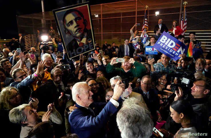 Democratic U.S. presidential candidate and former Vice President Joe Biden takes a picture as supporters hold up a 