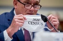 Census Bureau Director Steven Dillingham holds up his mask with the words 