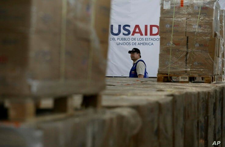 A man walks past boxes of USAID humanitarian aid at a warehouse at the Tienditas International Bridge on the outskirts of Cucuta, Colombia, Feb. 21, 2019, on the border with Venezuela. Venezuela's President Nicolas Maduro said he’s weighing whether to shut down the border with Colombia, where the bulk of aid meant for Venezuela is being stockpiled and exiled leaders have been gathering ahead of a fundraising concert Friday. (AP Photo/Fernando Vergara)
