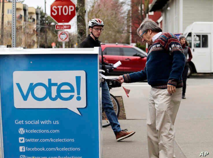 Voters drop off ballots in the Washington State primary, Tuesday, March 10, 2020 in Seattle. Washington is a vote by mail state…