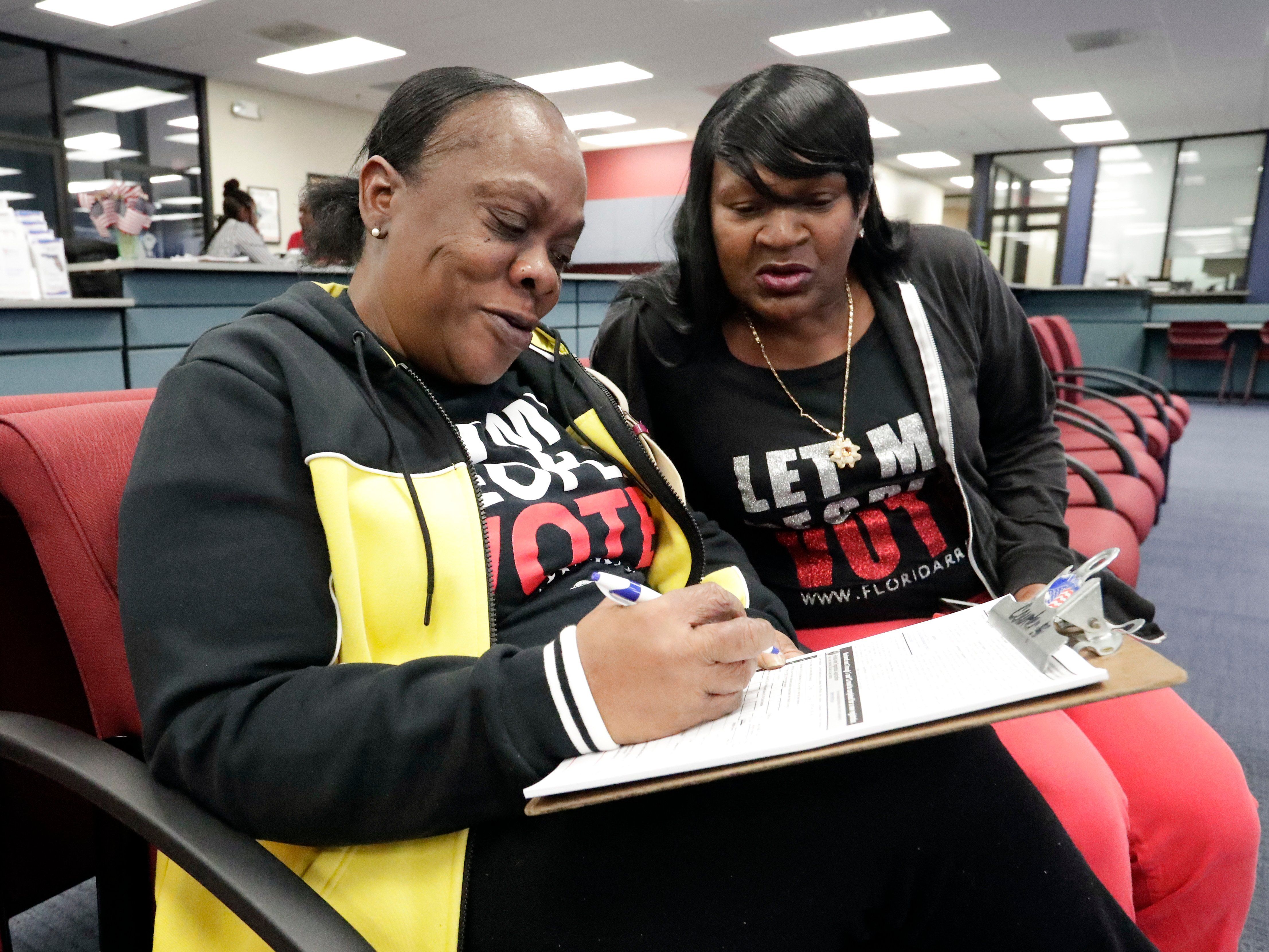 Former felon Yolanda Wilcox, left, fills out a voter registration form as her best friend Gale Buswell looks on at the Supervisor of Elections office Tuesday, Jan. 8, 2019, in Orlando, Fla. Former felons in Florida began registering for elections on…