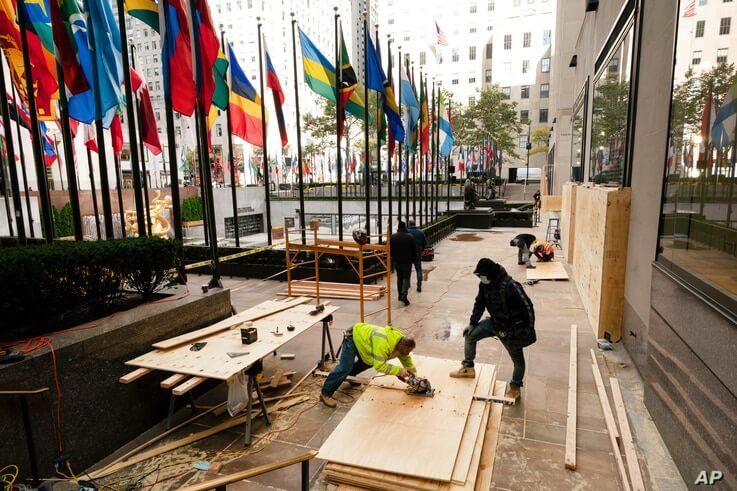 Workers board up a store in Rockefeller Center, Monday, Nov. 2, 2020, in New York ahead of Tuesday's contentious presidential…