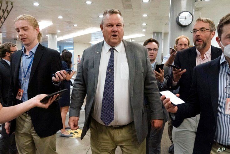 Sen. Jon Tester, D-Mont., talks to reporters as he walks to the Senate chamber ahead of a test vote scheduled by Democratic…