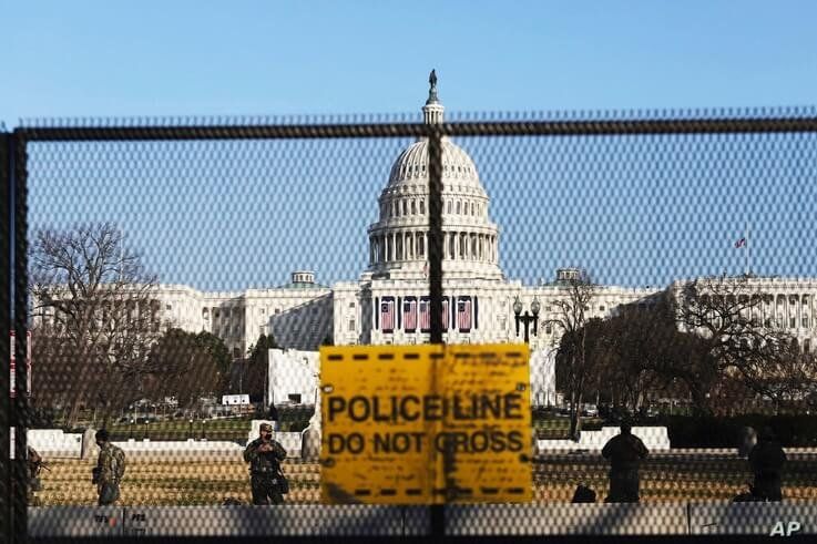 National guards are seen Wednesday, Jan. 13, 2021 on a fence that was erected to reinforce security at the Capitol in…