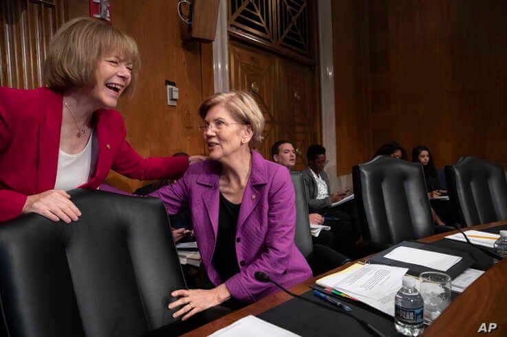 Sen. Tina Smith, D-Minn., left, speaks with Sen. Elizabeth Warren, D-Mass., at the start of a Senate hearing with healthcare…